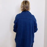 Person wearing a blue jacket standing against a white wall