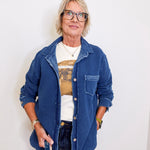 Person wearing a blue denim jacket over a graphic t-shirt against a white background