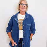 Person wearing a blue denim jacket over a graphic t-shirt against a white background