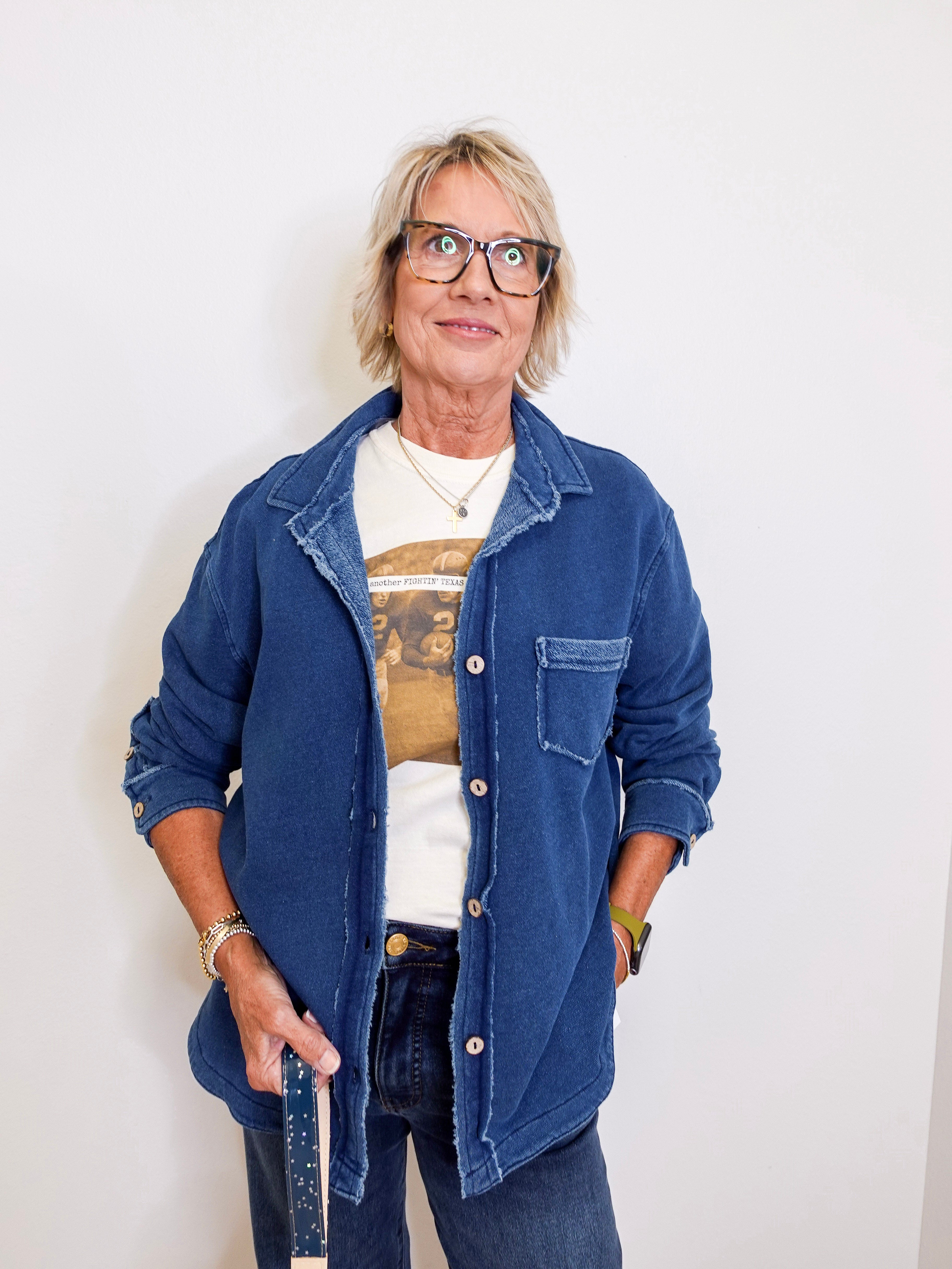 Person wearing a blue denim jacket over a graphic t-shirt against a white background