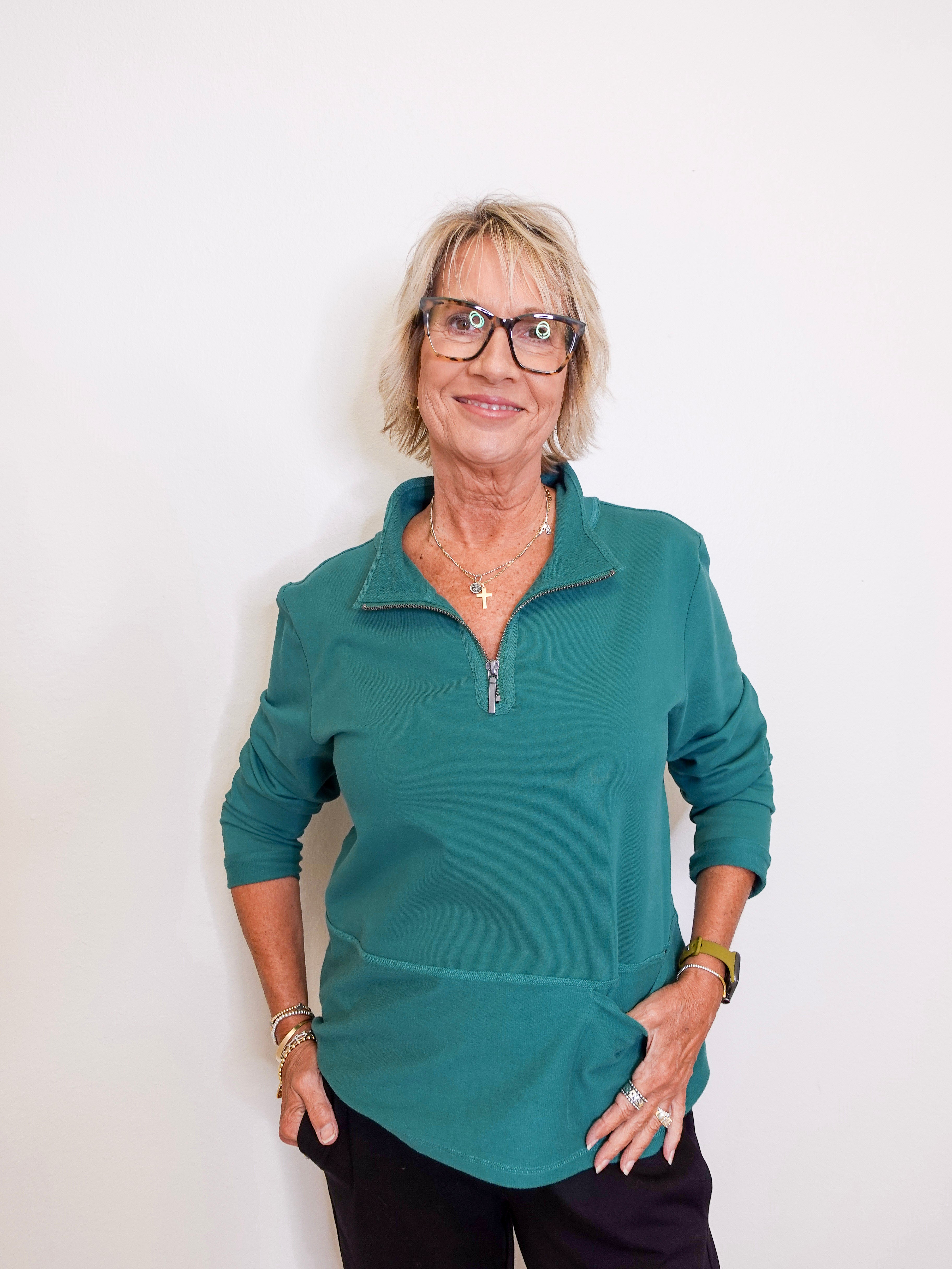 Woman wearing a teal long-sleeve shirt against a white background