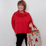 Woman in red top holding a decorative bag against a white background