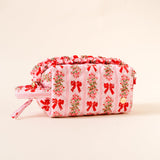 Pink cosmetic bag with floral and bow pattern on a beige background