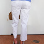 Person wearing a blue and white striped top with white pants, standing on a brown floor.