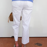 Person wearing a blue and white striped top with white pants, standing on a brown floor.