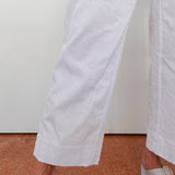 White pants being worn on a person standing on a brown floor.