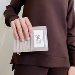 woman holding Beige passport holder with a zipper containing an Australian passport on a white background