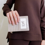 woman holding Beige passport holder with a zipper containing an Australian passport on a white background