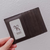 Brown leather wallet held by a hand with 'Hobo' logo on a light gray background