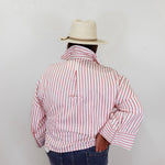 Person wearing a red and white striped shirt and a beige hat against a plain background
