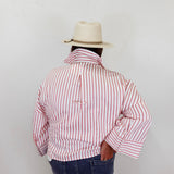 Person wearing a red and white striped shirt and a beige hat against a plain background