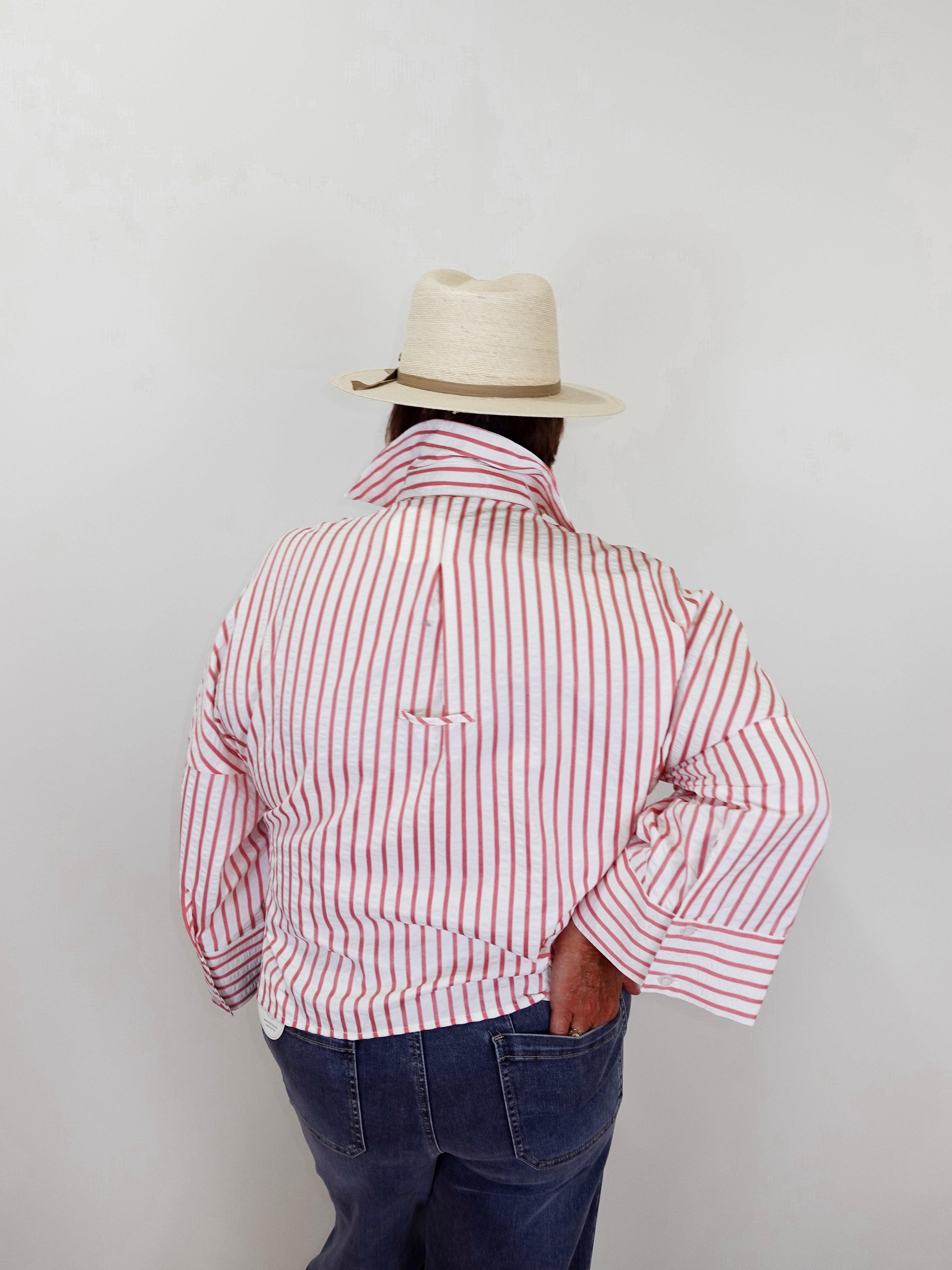 Person wearing a red and white striped shirt and a beige hat against a plain background