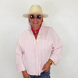 Person wearing a red and white striped shirt, blue jeans, sunglasses, and a beige hat against a plain background.
