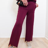 Person wearing a burgundy outfit with wide-leg pants and leopard print shoes on a light wooden floor.