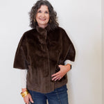 Woman wearing a brown fur cape against a white background