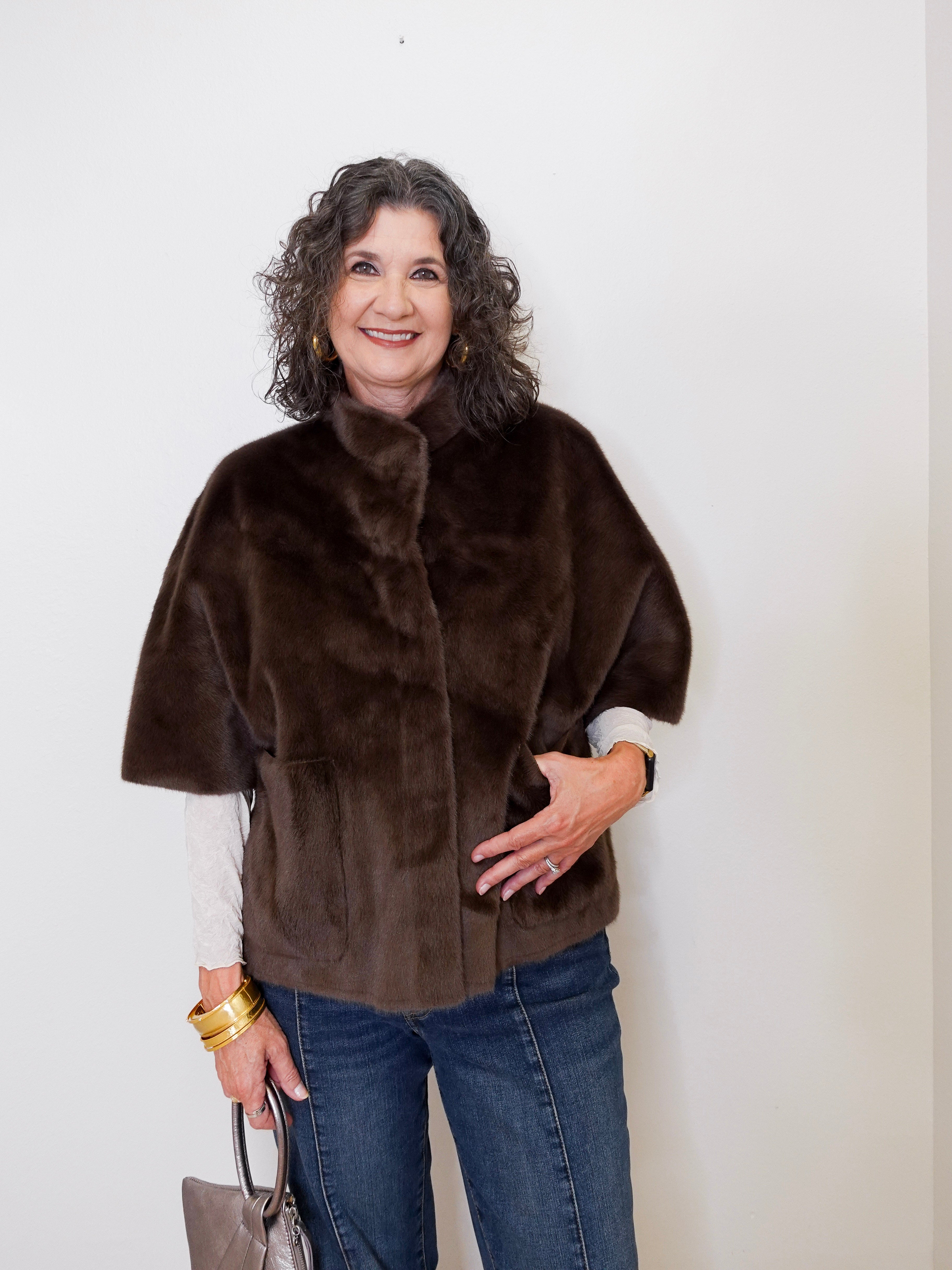 Woman wearing a brown fur cape against a white background