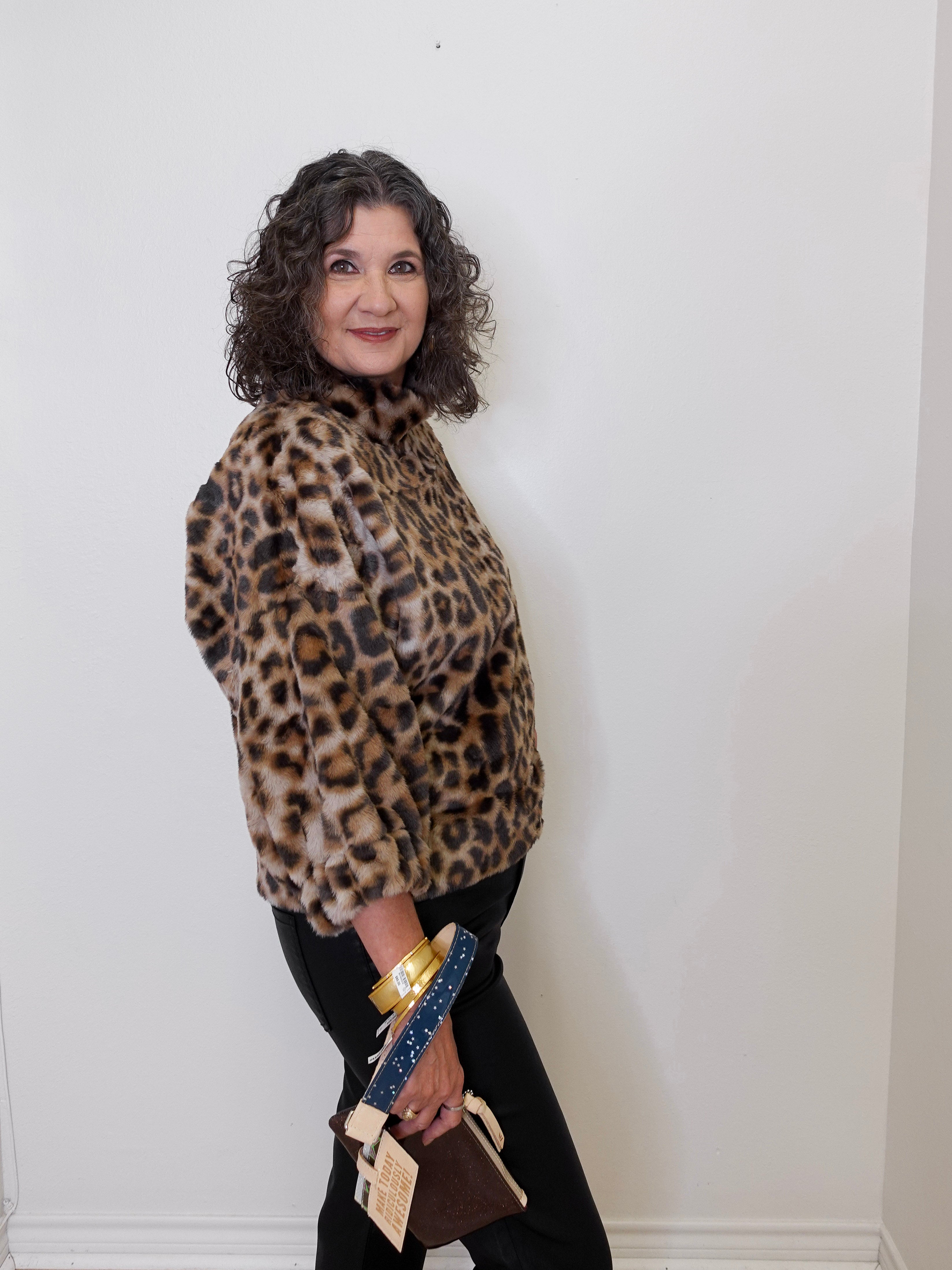 Woman wearing a leopard print jacket against a white wall