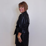 Woman wearing a black dress against a plain white wall