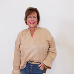 Woman wearing a beige blouse and blue jeans against a white background