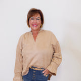 Woman wearing a beige blouse and blue jeans against a white background