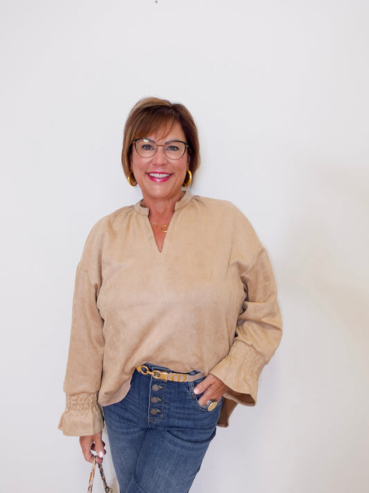 Woman wearing a beige blouse and blue jeans against a white background