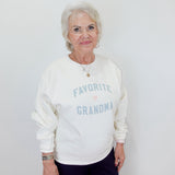 Woman wearing a white sweatshirt with 'Favorite Grandma' text on a plain background
