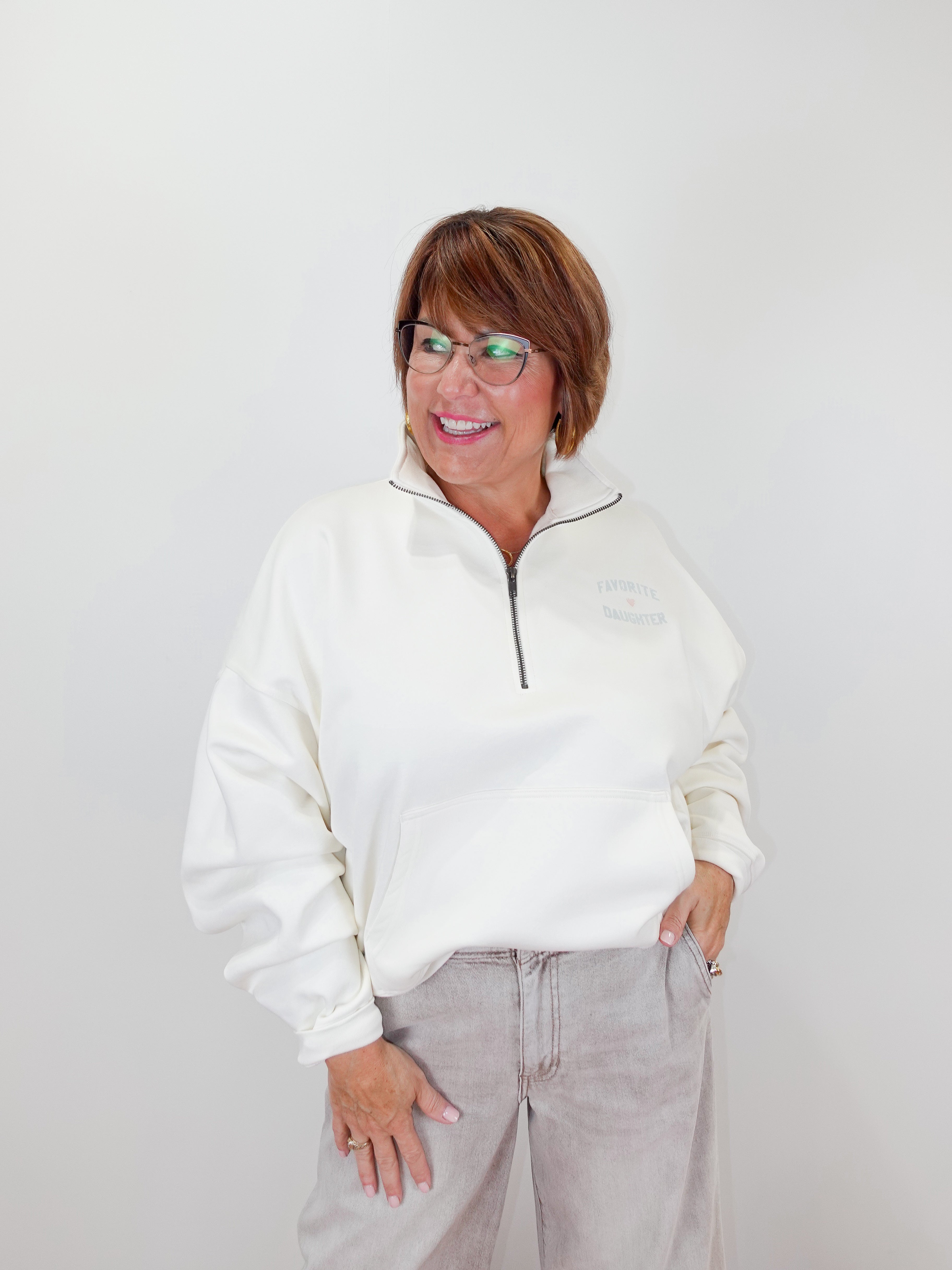 Person wearing a white sweater and light gray pants against a plain background