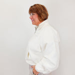 Person wearing a white jacket against a plain background