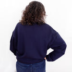 Person wearing a navy blue sweatshirt and jeans on a white background