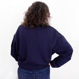 Person wearing a navy blue sweatshirt and jeans on a white background