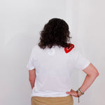 Person wearing a white t-shirt with a red heart design on the back, standing against a plain background.