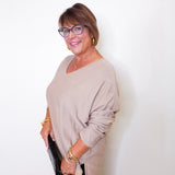 A woman wearing a v-neck jewel embellished sweater in front of a white wall.
