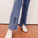 Person wearing blue jeans and white sneakers on a neutral background