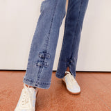 Person wearing blue jeans and white sneakers on a neutral background