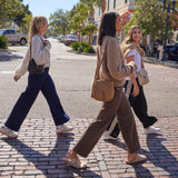 Three women walking on a sidewalk in an urban setting