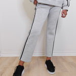 Person wearing gray tracksuit with black trim on a light wooden floor.