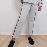 Person wearing gray tracksuit with black trim on a light wooden floor.