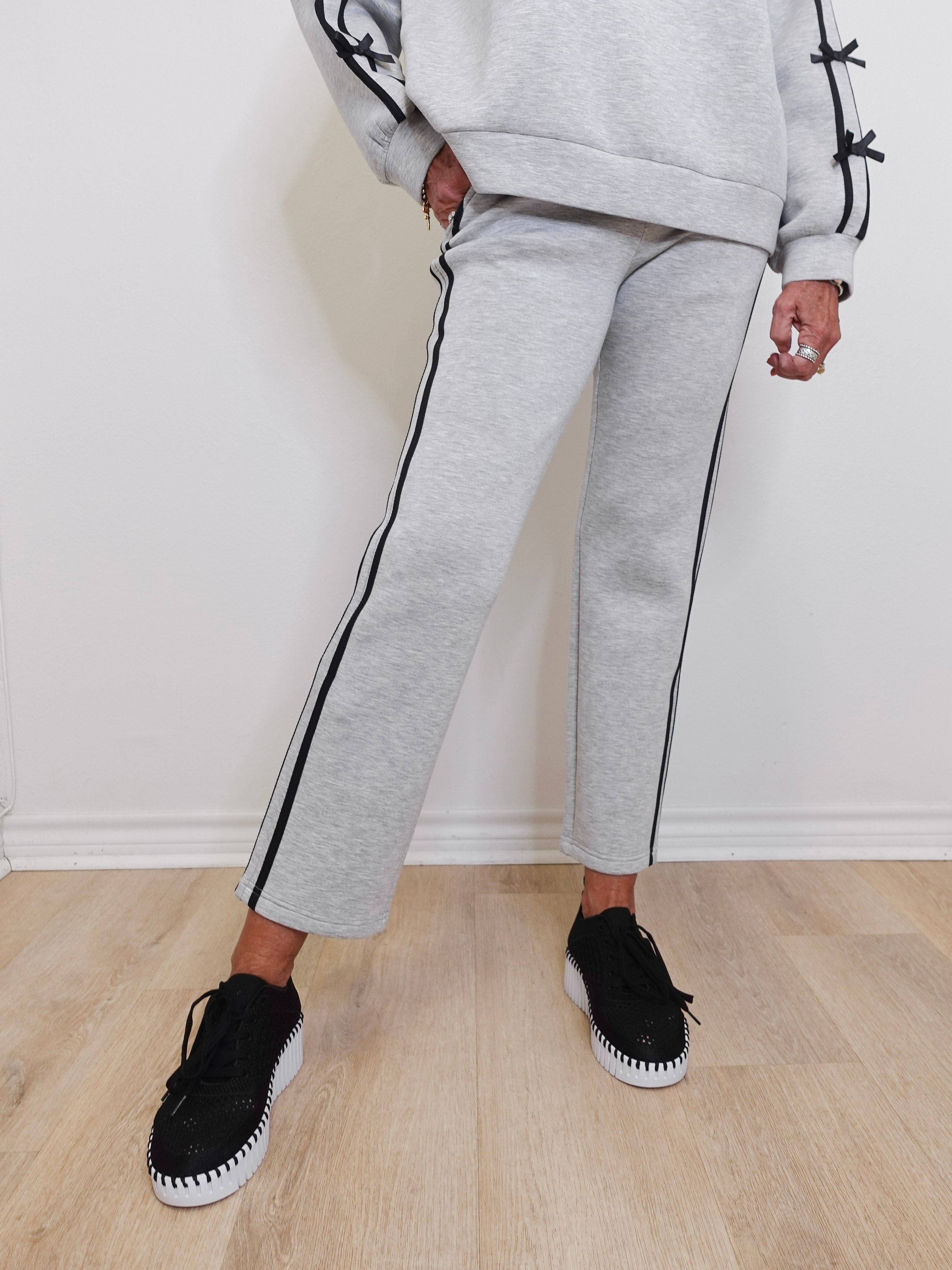 Person wearing gray tracksuit with black trim on a light wooden floor.