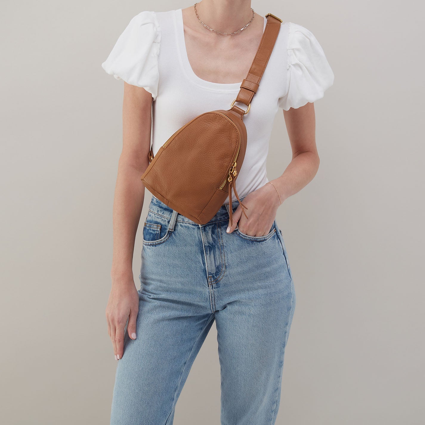 Hobo Fern Sling in warm honey leather with adjustable strap and zip closure.