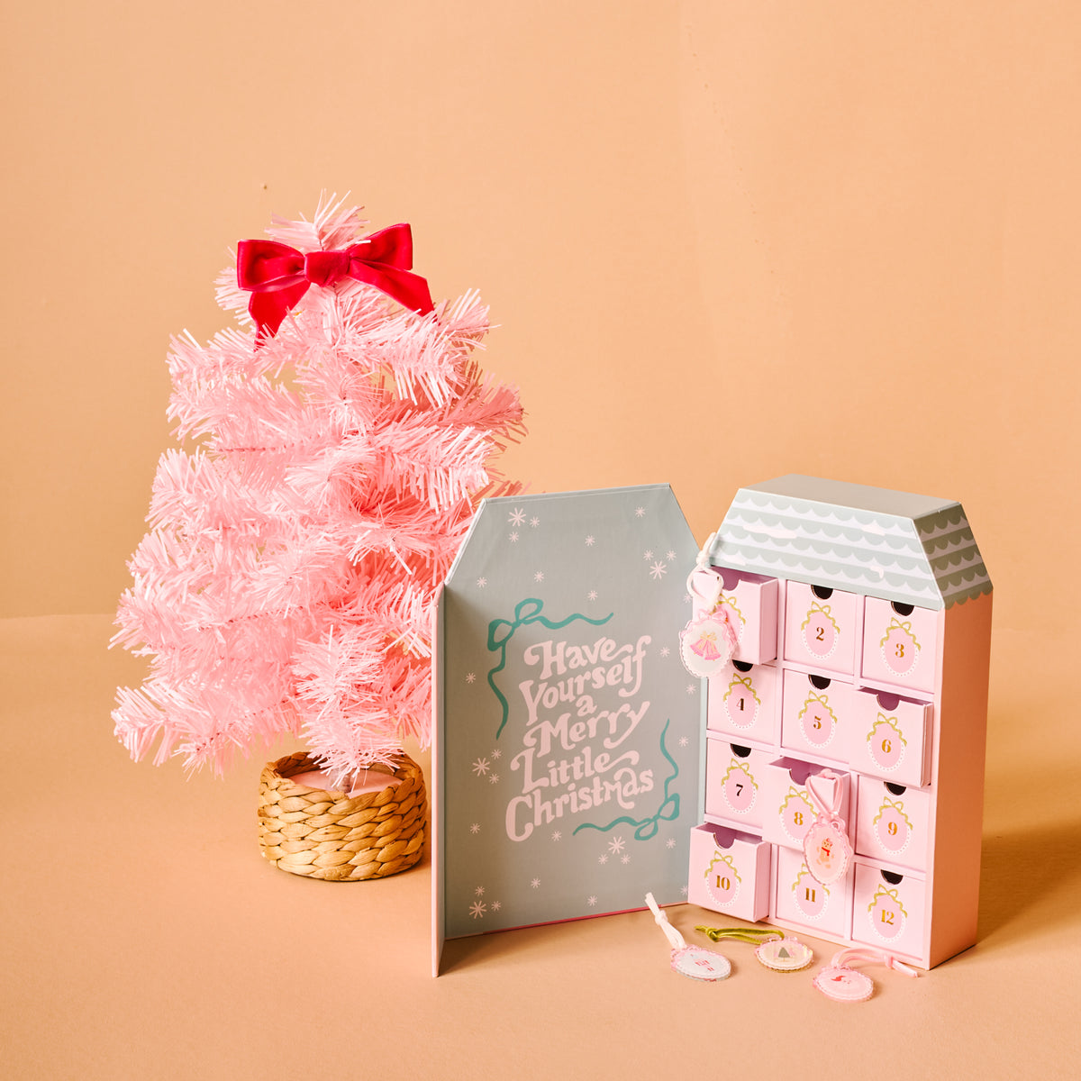 Pink Christmas tree with a house-shaped advent calendar on a beige background