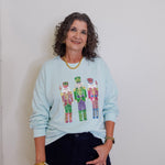 Woman wearing a light blue sweatshirt with colorful graphic design against a plain background