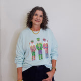 Woman wearing a light blue sweatshirt with colorful graphic design against a plain background