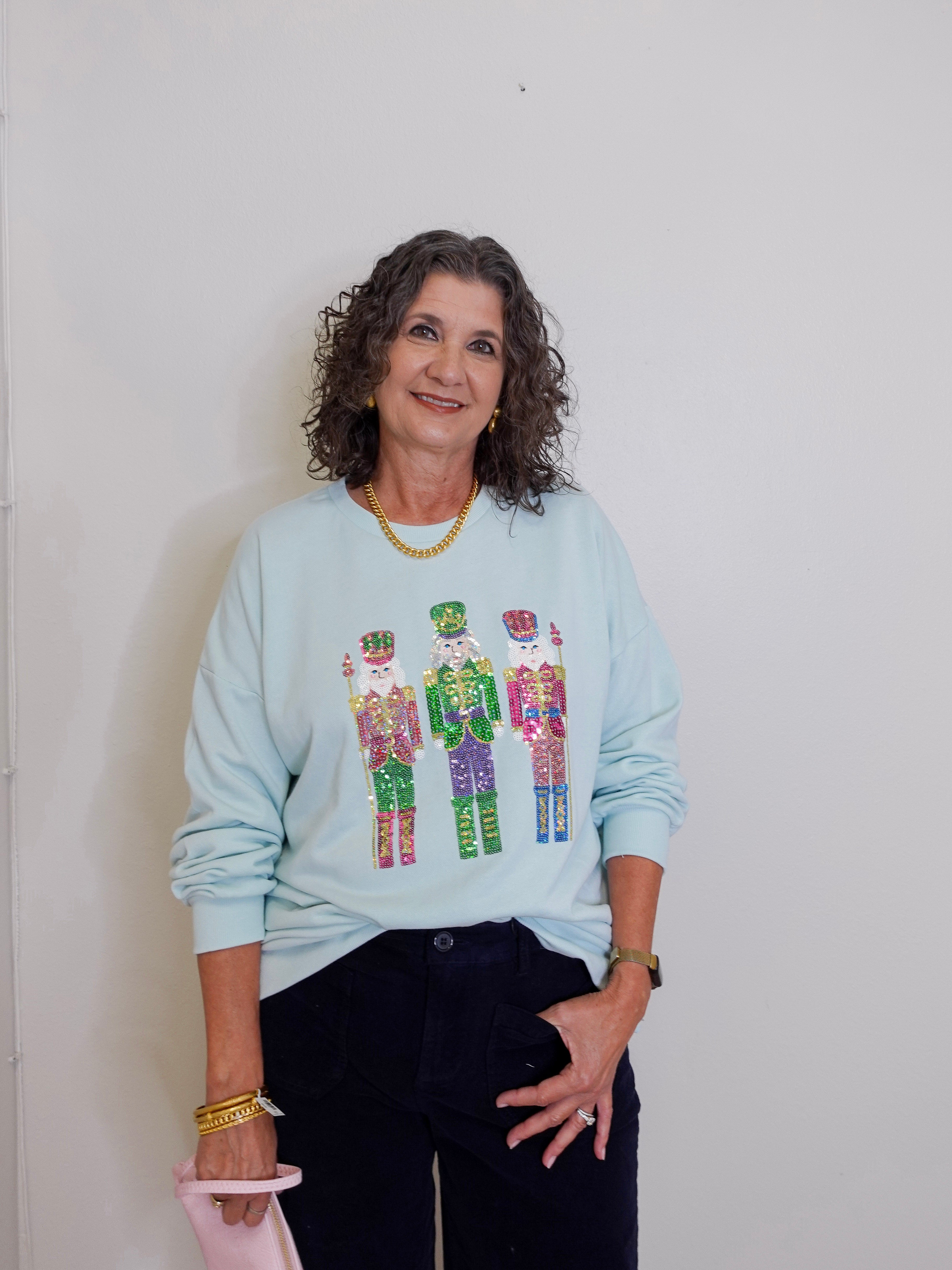 Woman wearing a light blue sweatshirt with colorful graphic design against a plain background