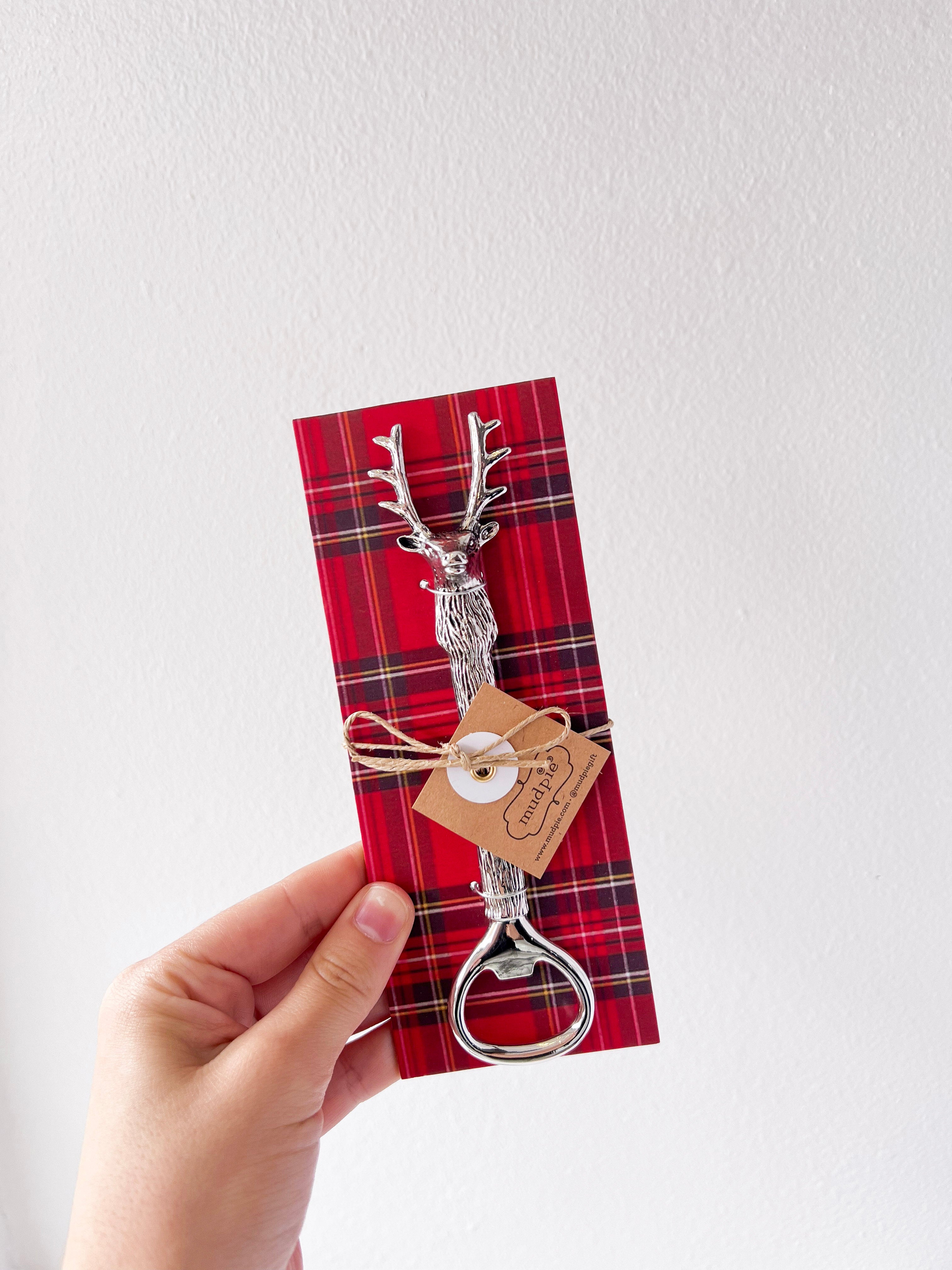 Red plaid napkin with a bottle opener and tag held by a hand on a white background