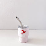 White tumbler with a red and white design and a metal straw on a light gray background