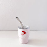 White tumbler with a red and white design and a metal straw on a light gray background