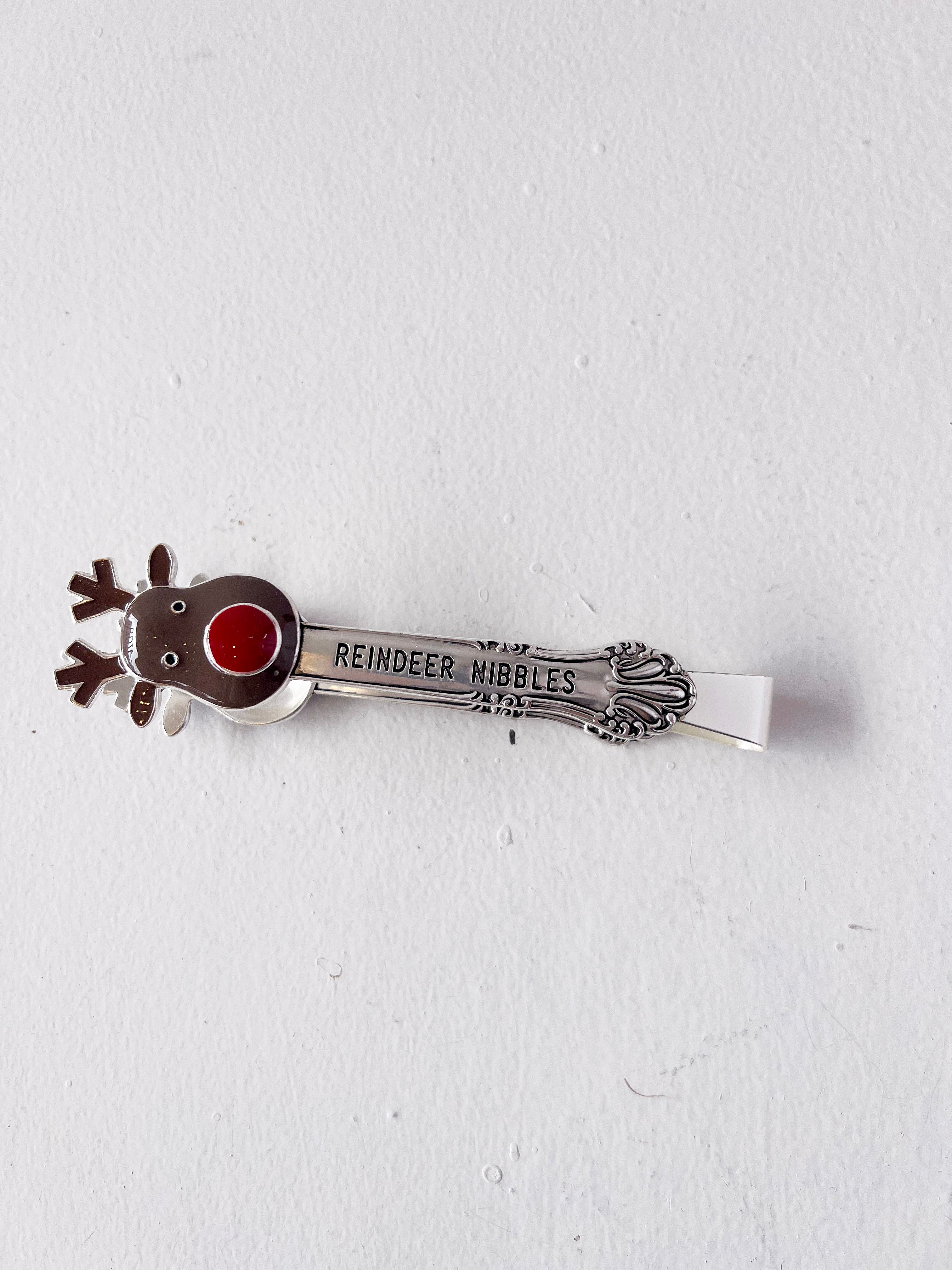 Metallic reindeer-shaped object with a red nose on a white background