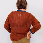 Person wearing a brown knitted sweater with a white background
