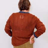 Person wearing a brown knitted sweater with a white background