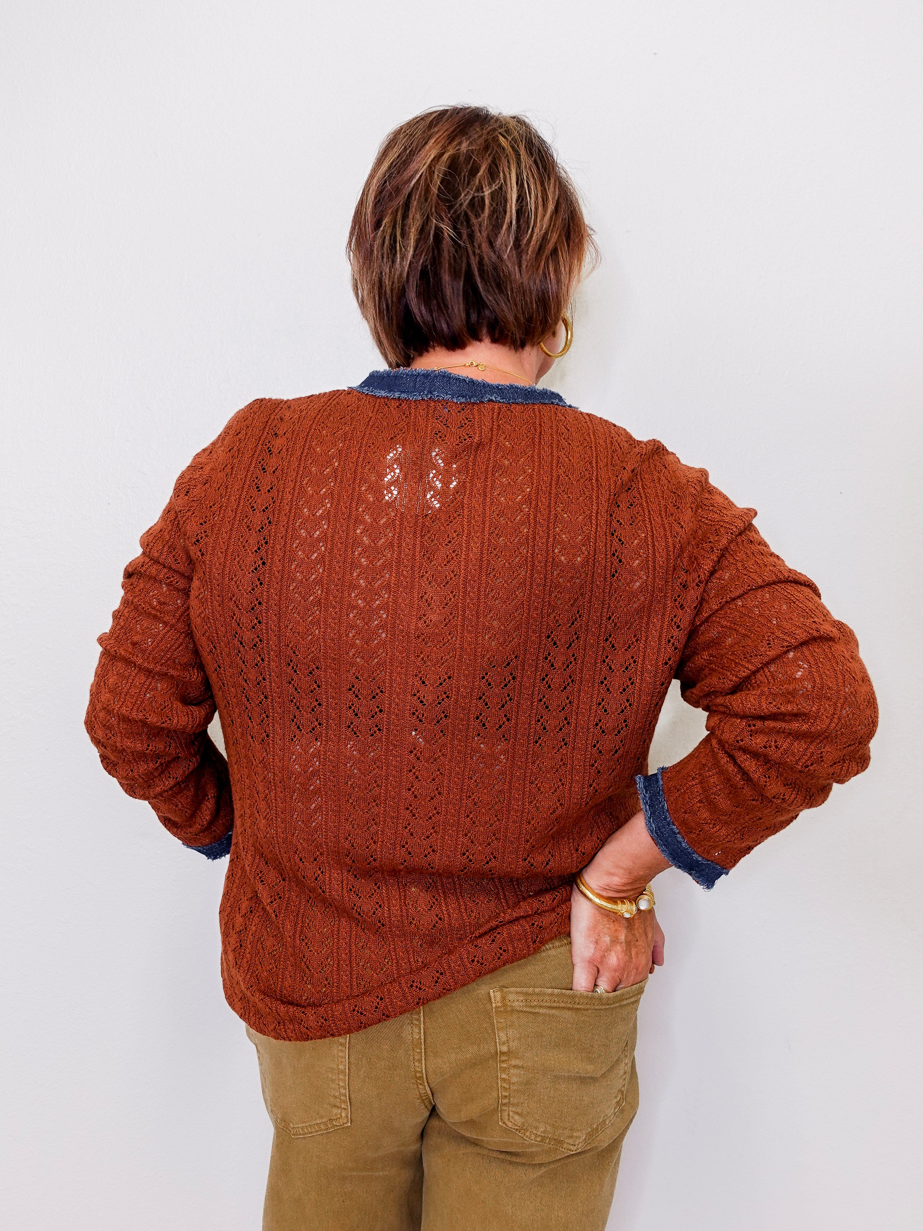 Person wearing a brown knitted sweater with a white background
